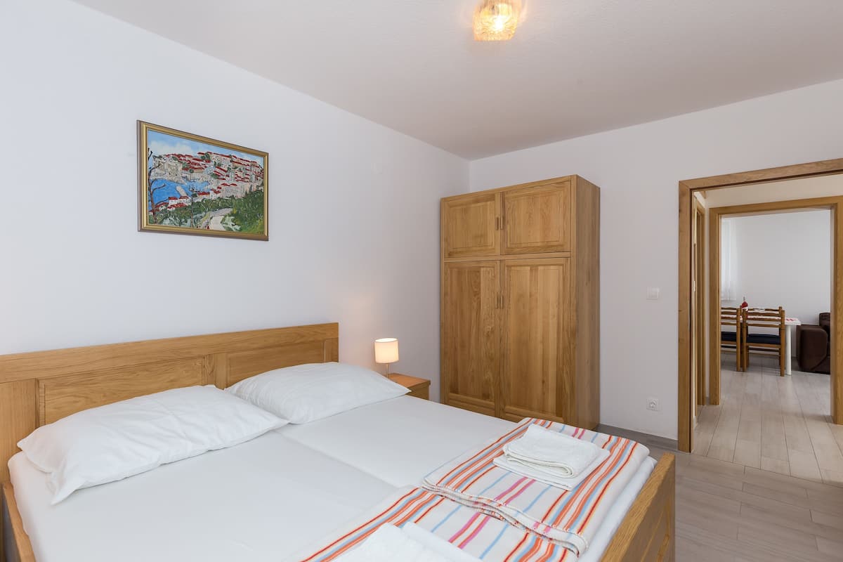 A bedroom with a wooden bed, a nightstand, a wardrobe, and a painting on the wall.