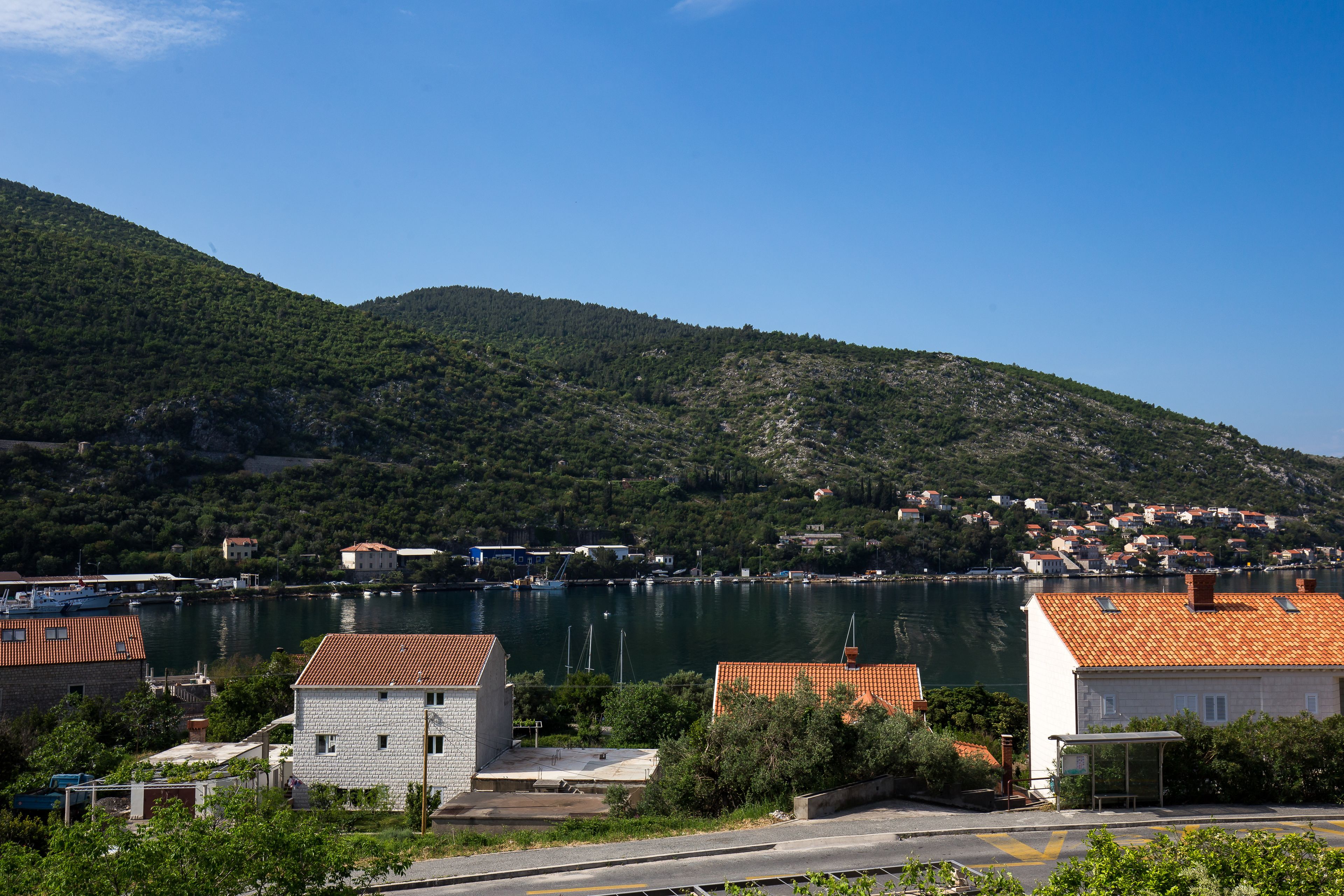 A coastal town with buildings near a body of water, surrounded by hills.