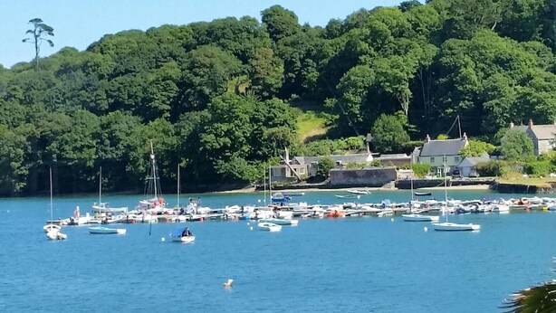 A coastal village with a marina filled with boats, surrounded by dense green hills and traditional houses. - Mandeley Guest House (Helston)