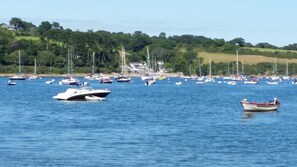 A marina with various boats anchored in calm waters, surrounded by lush greenery and a hilly landscape. - Mandeley Guest House (Helston)