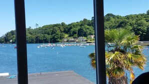 A marina with boats docked, a clear blue sky, and a forested hillside in the background. - Mandeley Guest House (Helston)