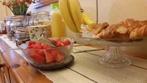 A breakfast buffet with fruits, pastries, and a juice dispenser. - Mandeley Guest House (Helston)