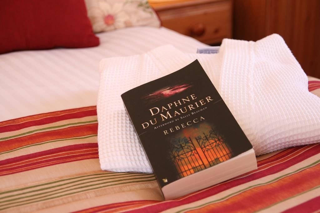 A book titled 'Daphné du Maurier' on a bed with a striped bedspread.