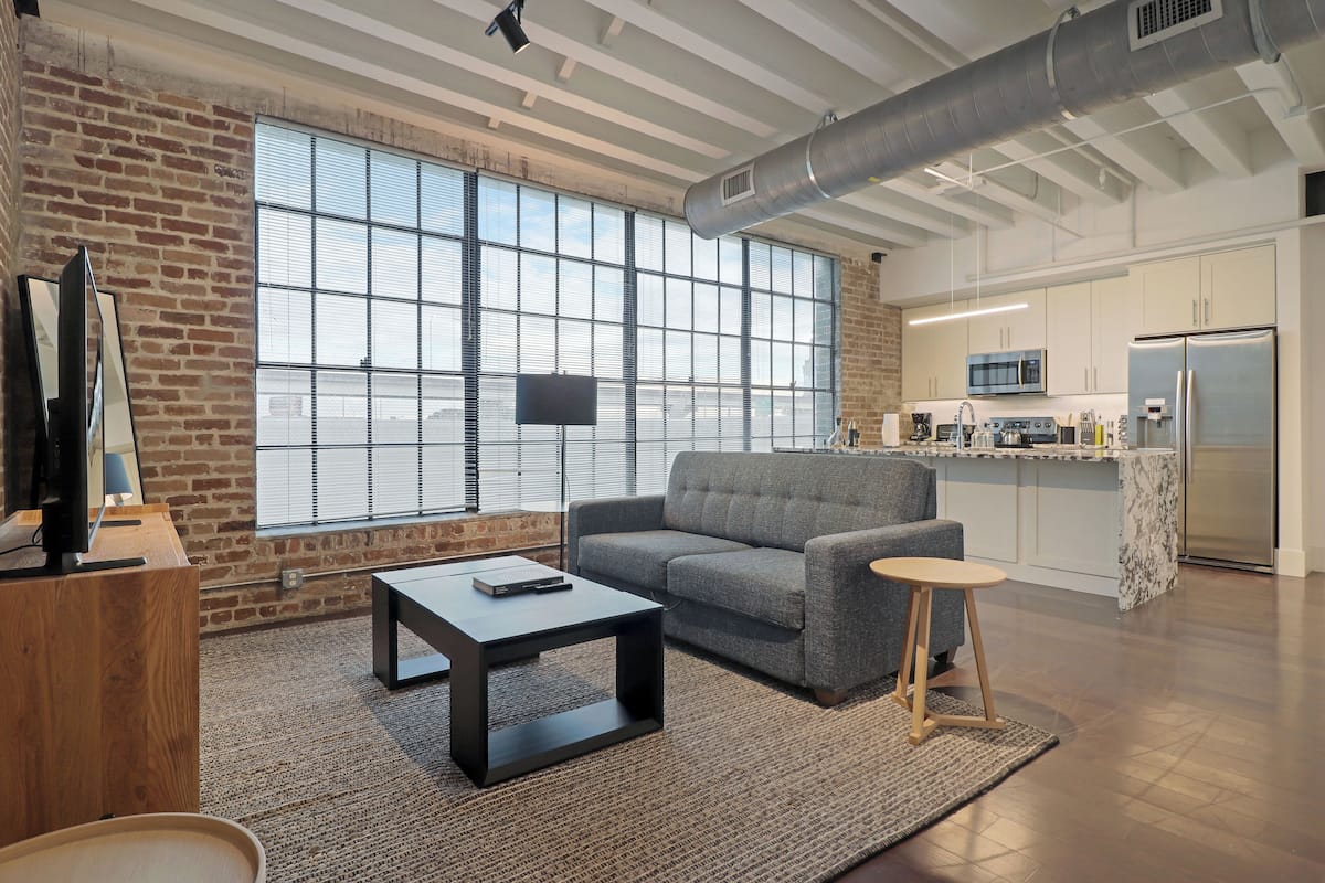 A modern living room with a sofa, coffee table, and a TV on a wooden stand.