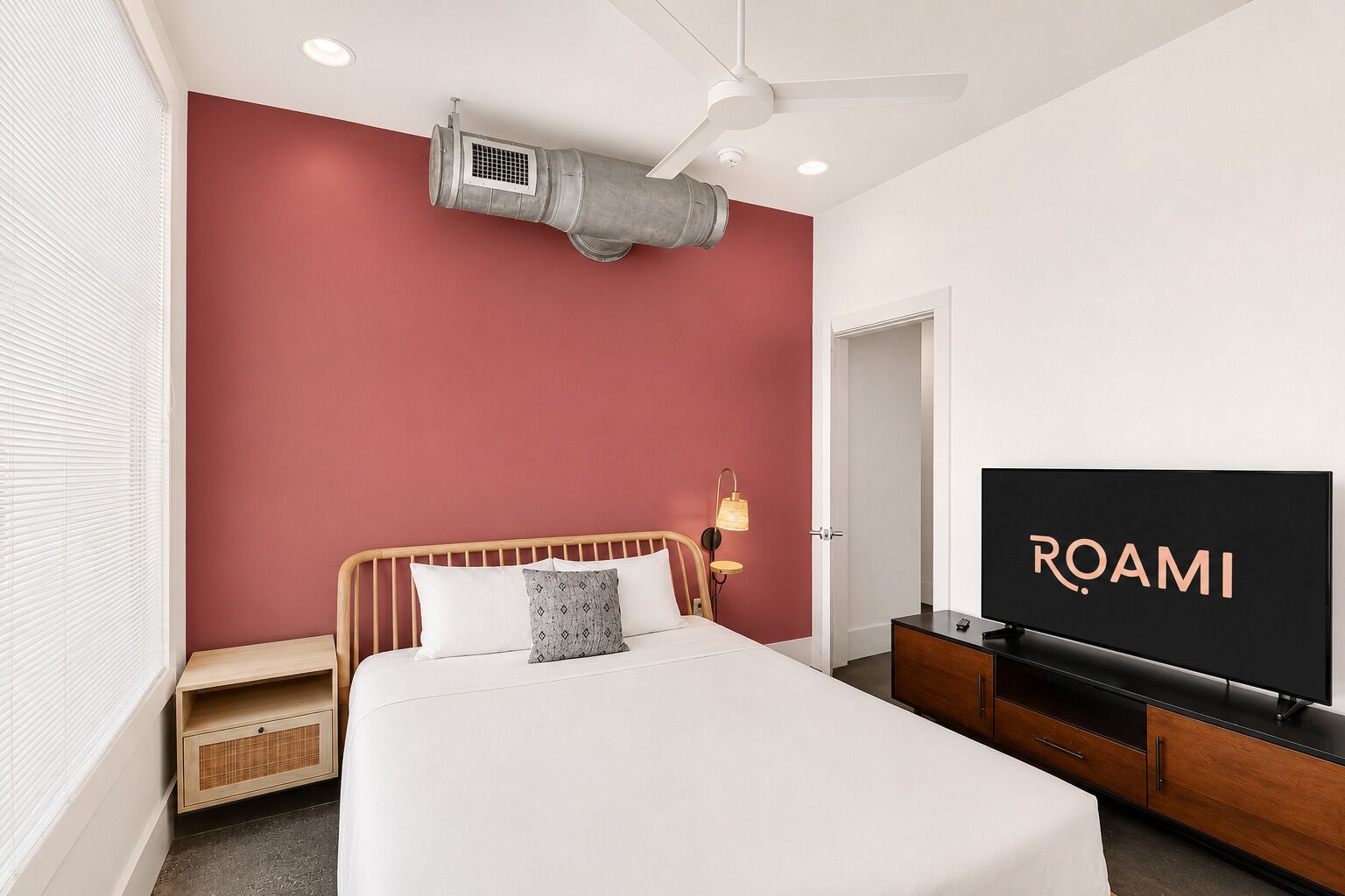 A hotel room with a bed, a television, a wardrobe, and a ceiling fan.