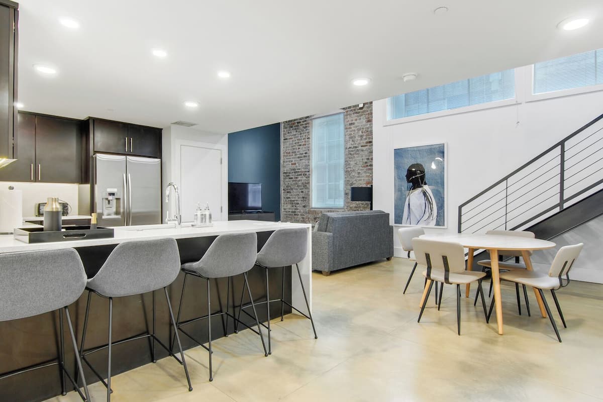 A modern kitchen with a central island, bar stools, and a dining area with a table and chairs.