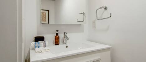 A white bathroom with a sink, mirror, and towel rack.