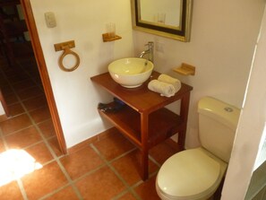 A bathroom with a white toilet, a wooden vanity with a white sink, and a mirror above the sink. - Los Delfines Lodge (Cahuita)