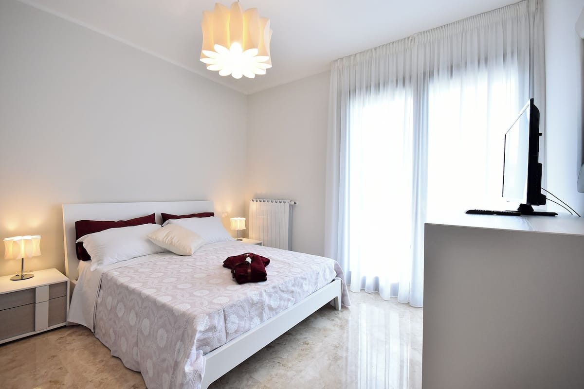 Une chambre à coucher avec un lit, des lampes de chevet, un téléviseur et un radiateur.