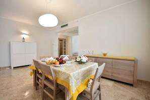 Un comedor con una mesa dispuesta para dos personas, un armario blanco y una encimera amarilla.