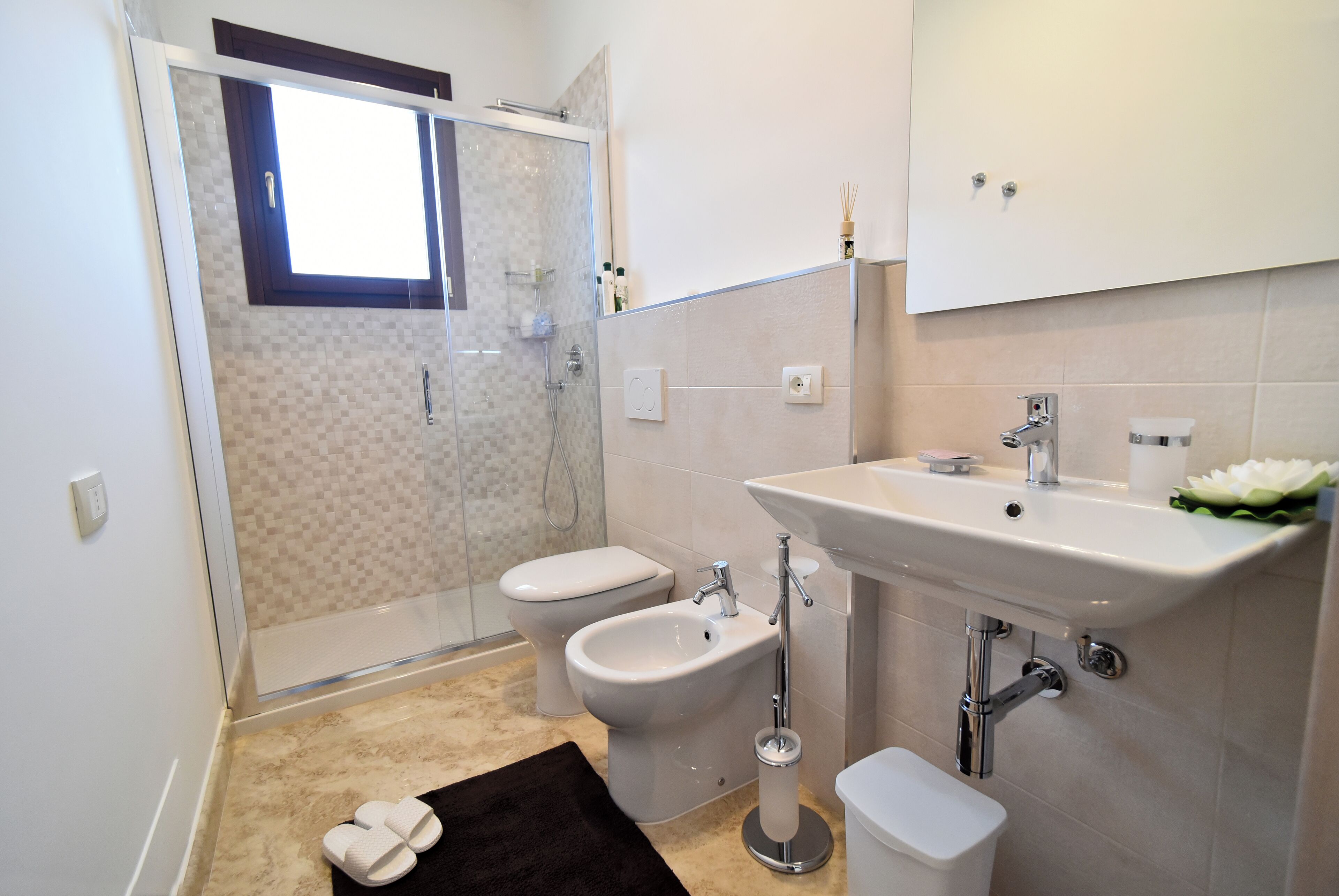 A modern bathroom with a shower, bidet, toilet, and sink.