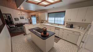 A modern kitchen with white cabinets, a central island, and a large window.