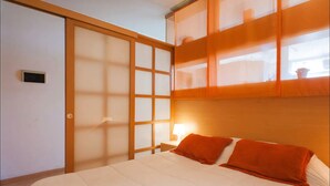 A hotel room with a bed, a sliding door, and a nightstand with a lamp. - Departamento Palermo con Balcon (Buenos Aires)