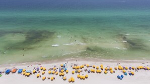 Ein Strand mit vielen gelben Sonnenschirmen und freiem Blick auf den Ozean.