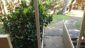 Una escalera de madera que lleva a una zona cubierta con barandilla de metal.
