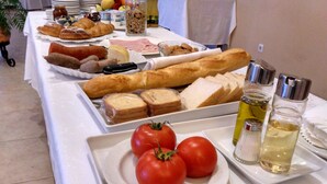 Ein reichhaltiges Buffet mit verschiedenen Speisen, darunter Brot, Tomaten und Beilagen.