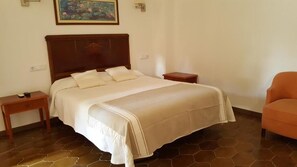 Ein Schlafzimmer mit einem großen Bett, zwei Nachttischen, einem Beistelltisch und einem Sessel.