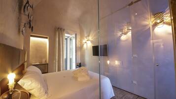 A hotel room with a bed, bedside table, lamp, and a wall-mounted TV.