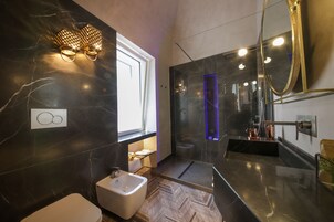 Egy modern fürőszoba márványburkolatú fallal, mosdókagylóval, WC-vel és zuhanyzóval.