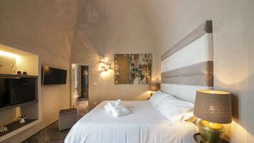Ein Hotelzimmer mit einem großen Bett, einem Flachbildfernseher, einem Wandbild und einer Nachttischlampe.