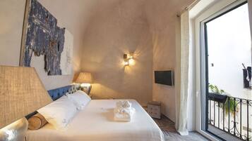 A hotel room with a bed, a wall-mounted TV, a window with a view, and a nightstand.