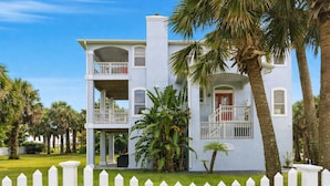 A two-story building with a white exterior, a red door, and a balcony on the upper floor. - Vilano Beach Pool Home-Ocean Views (St. Augustine)