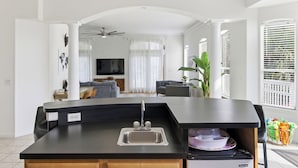 A modern kitchen with a black countertop, stainless steel sink, and a built-in dishwasher. - Vilano Beach Pool Home-Ocean Views (St. Augustine)