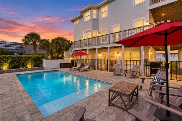 A swimming pool with lounge chairs and umbrellas, a covered patio area, and a multi-story building with balconies. - Heated Pool-Ocean Views-Steps to Beach (St. Augustine)