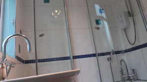 Une salle de bain équipée d’un lavabo, d’un miroir et de deux pommes de douche.