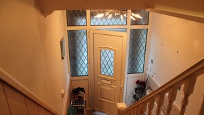 Un escalier avec des rampes en bois et une porte dotée de panneaux en verre dépoli.