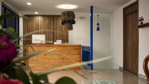 A reception area with a wooden reception desk, a blue pillar, and a hanging light fixture. - El reloj casa hotel (Filandia)