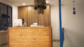 Una reception con scrivania in legno, una finestra con cornice blu e un lampadario.