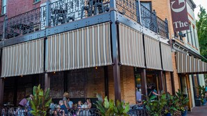A corner building with a balcony and outdoor seating area.
