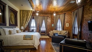 A room with a large bed, a sofa, and a television.
