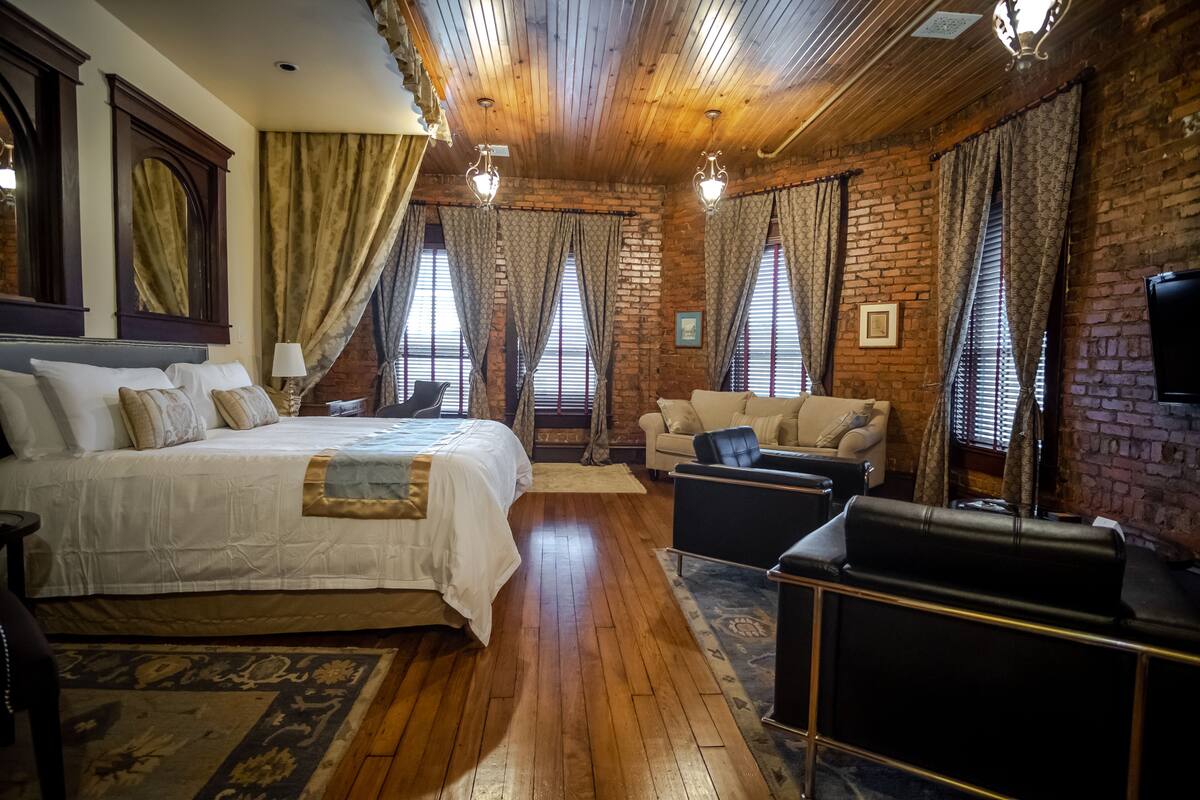 A room with a large bed, a sofa, and a television.