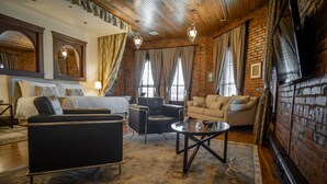 A hotel room with a bed, two armchairs, a sofa, a coffee table, and a brick wall.