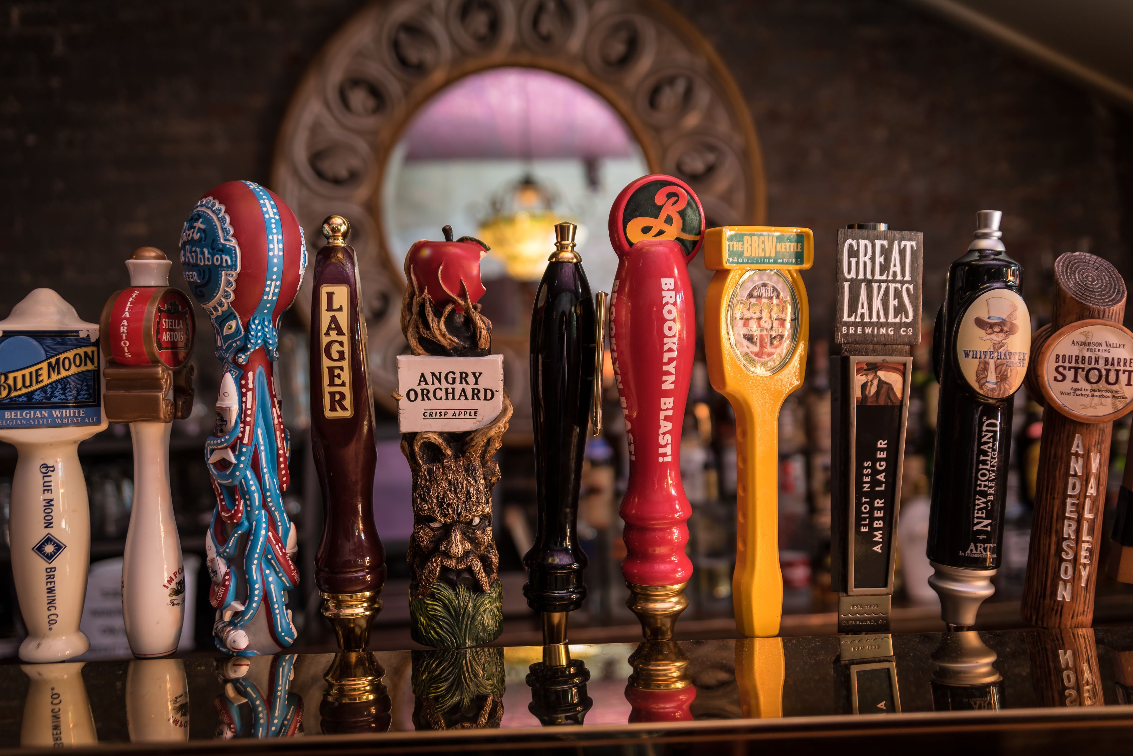 A variety of beer taps with labels such as "BELGIAN WHITE," "LAGER," "ANGRY ORCHARD," and "BROOKLYN BLAST."