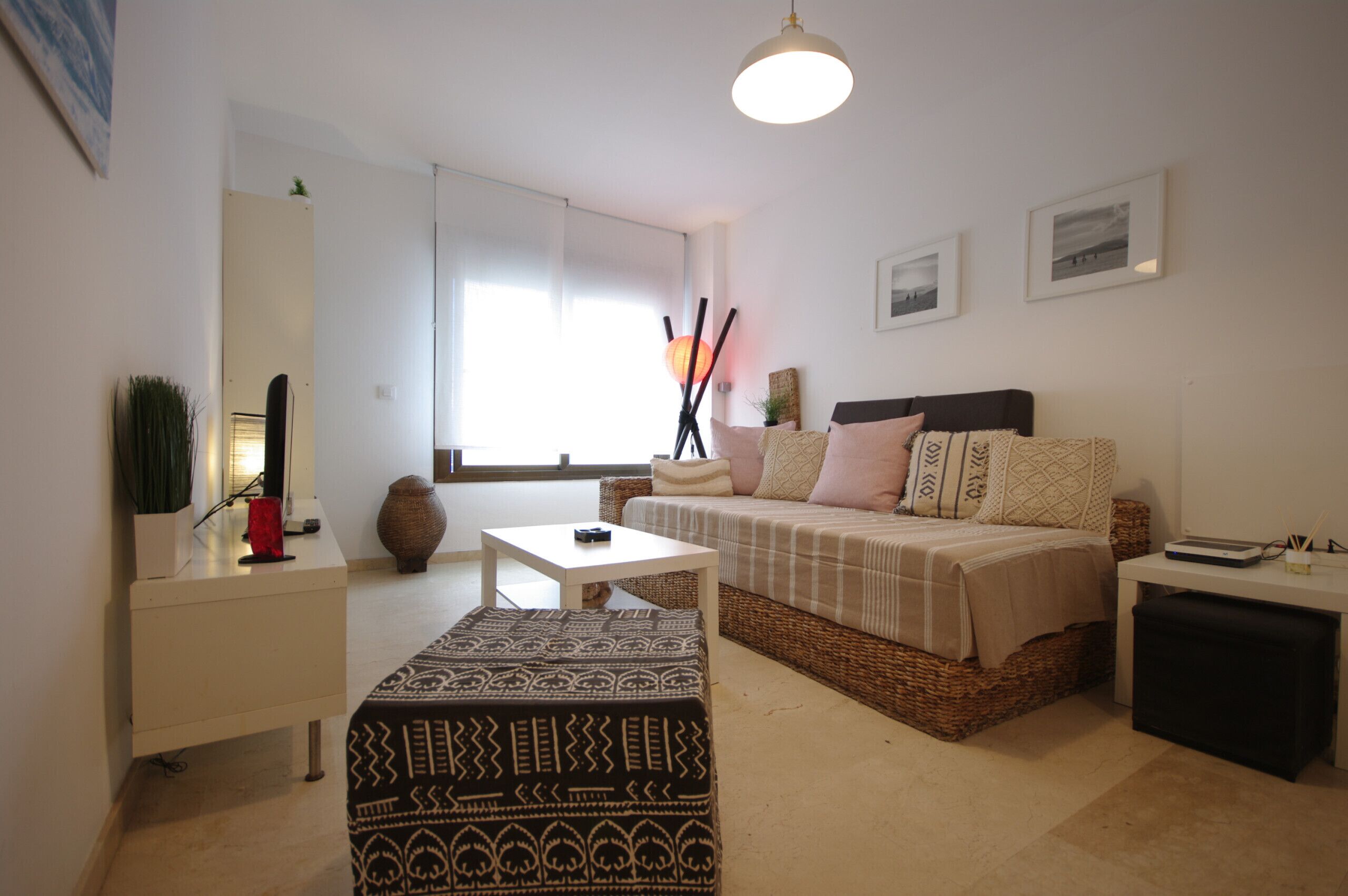 Une chambre à coucher moderne et bien éclairée, avec un lit, une table de chevet et un petit bureau.