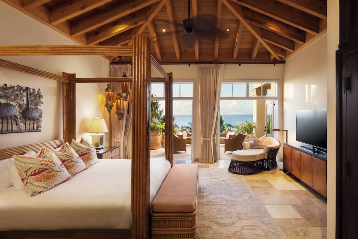 Ein geräumiges Schlafzimmer mit einem großen Bett, einer Sitzecke mit Blick und einem Fernseher.