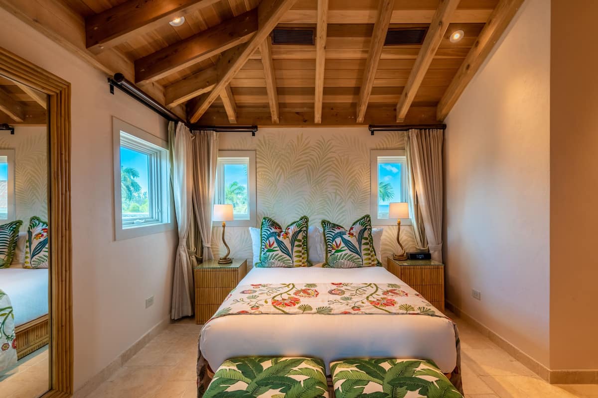 Ein geräumiges Schlafzimmer mit einem großen Bett, zwei Nachttischen und einer Decke mit freiliegenden Holzbalken.
