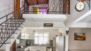 A spacious kitchen with a central island, a dining area with chairs, a staircase, and a clock on the wall. - Villa with Heated Pool (Black River)