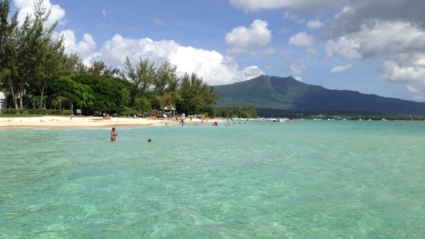 A beach with clear turquoise water, a sandy shore, and a mountain in the background. - Villa with Heated Pool (Black River)