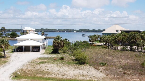 A coastal property with a covered parking area, a large body of water, and a distant shoreline. - Las Palmas 204 Two Bedroom Condo (Gulf Shores)