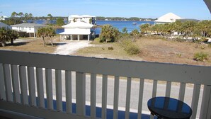 A view of a waterfront property with a covered patio, a small pool, and a clear blue sky. - Las Palmas 204 Two Bedroom Condo (Gulf Shores)