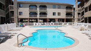 A swimming pool with lounge chairs and a white fence. - Las Palmas 204 Two Bedroom Condo (Gulf Shores)