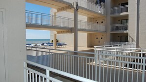 A multi-level outdoor balcony area with white railings and blue lounge chairs.