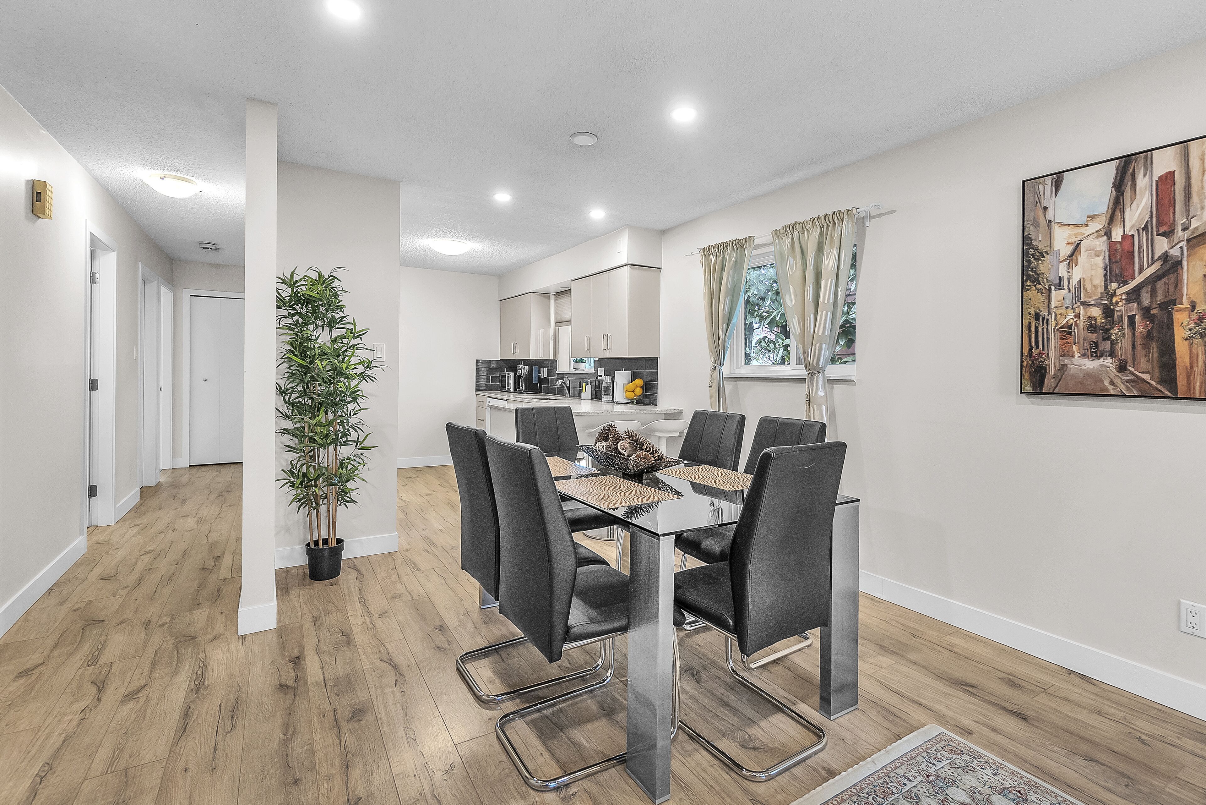 Un espace repas moderne avec une table en verre, des chaises noires et une plante en pot.
