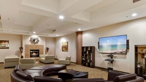A spacious living room with a fireplace, comfortable seating, a large flat-screen TV, and a beach-themed painting. - Bluebird Suites at the Warehouse District (Cleveland)