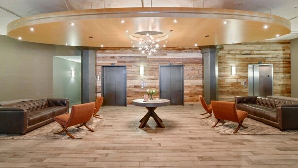 A lobby with a round table, leather sofas, and a wooden floor. - Bluebird Suites at the Warehouse District (Cleveland)