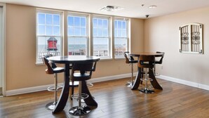 A dining area with a large window, a round table, and bar stools. - Bluebird Suites at the Warehouse District (Cleveland)
